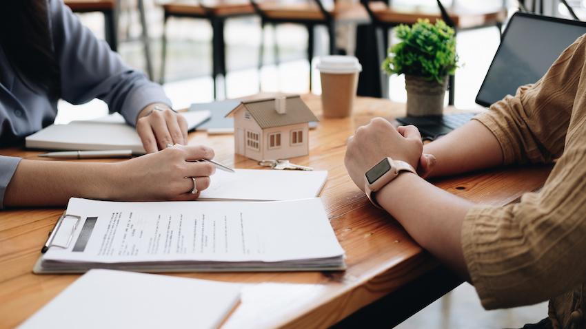 Two people sit across from each other discussing a loan