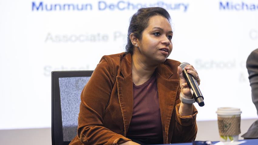 Woman sits in chair holding a microphone