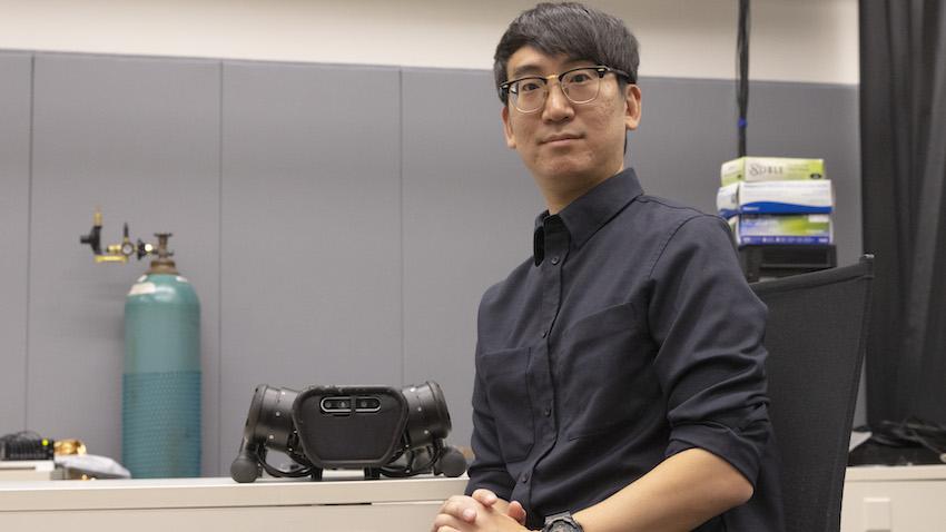 Man sits in chair next to four-legged robot